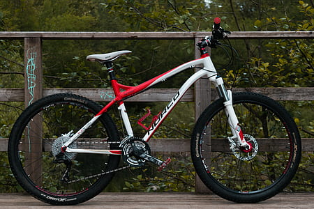 red and white hardtail bike beside brown fence thumbnail