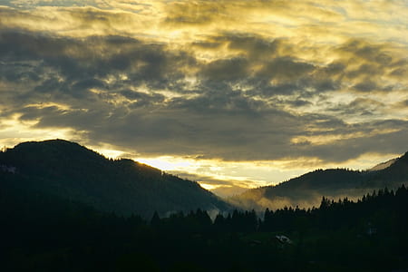 trees and mountains under cloudy sky thumbnail