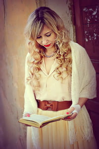 woman wearing white dress holding book while standing thumbnail