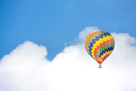 Yellow Blue and Green Hot Air Balloon Flying Near White Clouds thumbnail