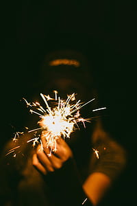 selective focus photography of person holding sparkler stick thumbnail