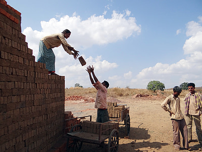 person's loading bricks on cart during daytime thumbnail