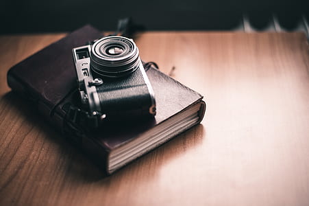 closeup photography of film camera on top of hardbound book on table thumbnail