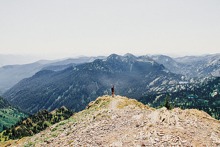 person standing on hill in front of mountains during daytime thumbnail
