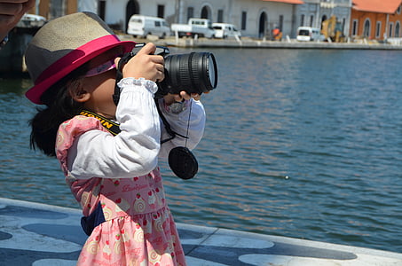 girl taking photo near body of water during daytime thumbnail