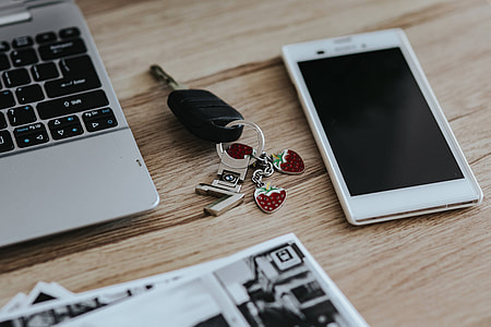 Black-and-white photos with a silver laptop, a smartphone, car keys, pencils and a camera thumbnail