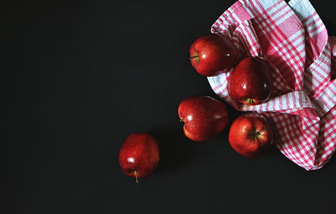 five red apples near red and white plaid towelette on black surface thumbnail