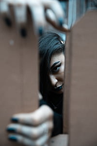 woman holding on brown fence while peeping thumbnail