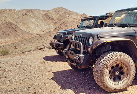 two black Jeep Wrangler SUVs on dirt road at daytime thumbnail