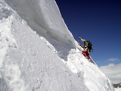 man climbing on snow coated mountain during daytime thumbnail
