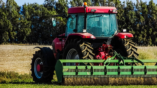 red and green farm tractor using cultivator on farm field at daytime thumbnail