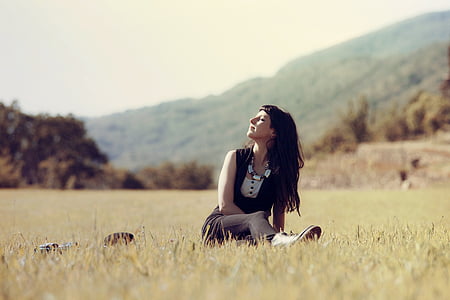 woman in white and black top sitting on grass field photo thumbnail