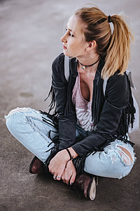 Blonde woman in a black jacket and ripped jeans by a green handrail thumbnail