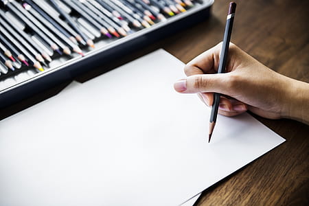 person holding pen leaning on white printer paper thumbnail