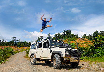 man in blue shirt above white SUV under clear blue sky during daytime thumbnail