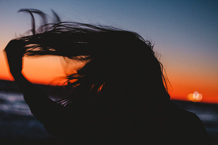 silhouette of long haired person in front of ocean water thumbnail