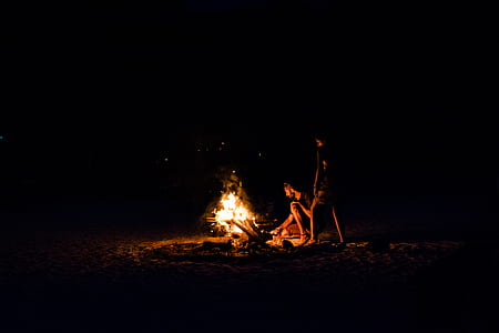 two persons on sand doing bonfire thumbnail
