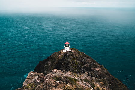 lighthouse on mountain near body of water thumbnail