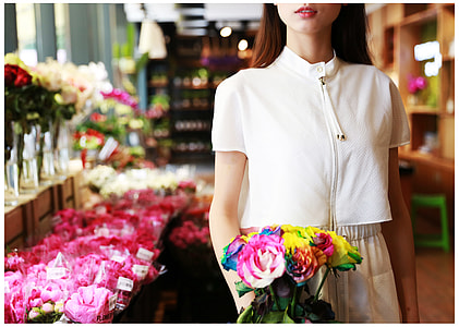 woman wearing white top holding out bouquet of flowers thumbnail