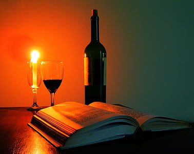 black glass bottle beside wine glasses filled with liquid and candle thumbnail