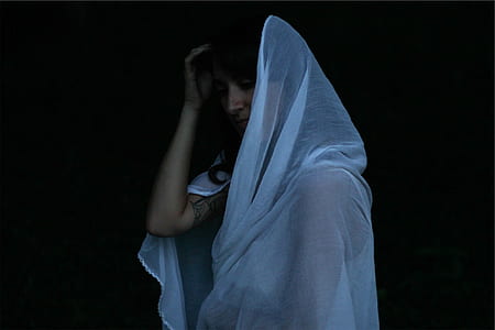 woman wearing white sheer headdress standing in black background thumbnail