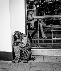 grayscale photo of woman sitting on bag beside wall thumbnail