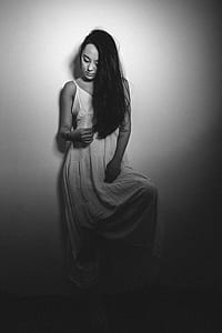 grayscale photo of woman leaning on white wall thumbnail