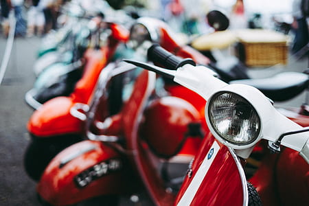 selective focus photography of red and white motor scooter near other motore scooters thumbnail