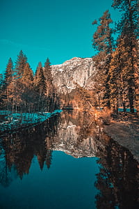 body of water near trees and mountain under blue sky at daytime thumbnail