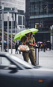 woman wearing green button-up shirt and dress pants holding green folding umbrella thumbnail