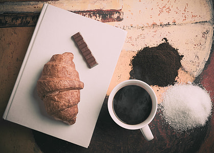 white ceramic coffee cup with coffee near black and white powders near baked bread on white ceramic plate thumbnail