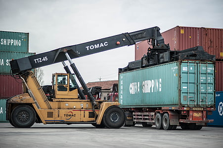 yellow and black Tomac heavy equipment near container tank at daytime thumbnail