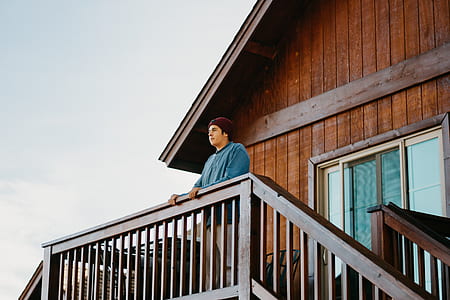 man standing on wooden house during daytime thumbnail
