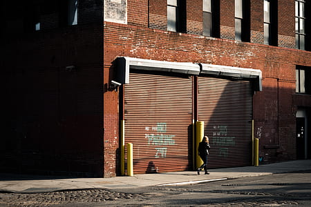 woman walking beside brown concrete building during daytime thumbnail