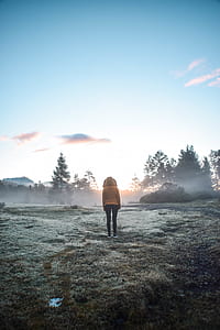 person in brown parka jacket standing on brown ground during sunrise thumbnail