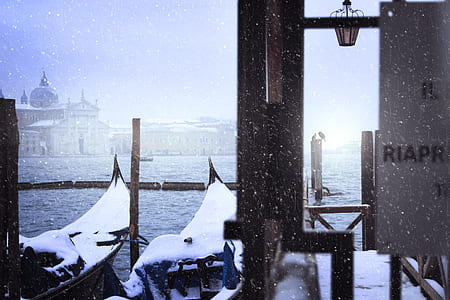 brown wooden boats covered with snow near sea water thumbnail