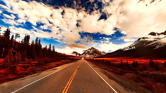 narrow asphalt road under white and blue sky thumbnail