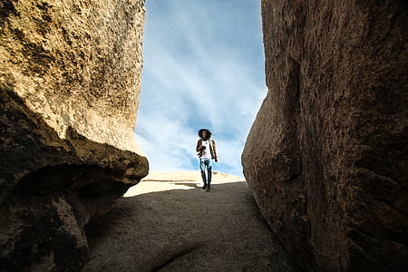 man walking between rocks during daytime thumbnail