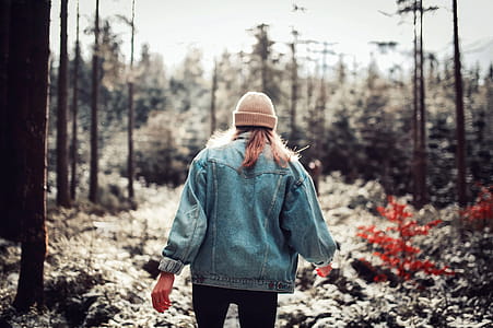 Woman Wearing Blue Denim Jacket and White Beanie Walking in the Forest thumbnail
