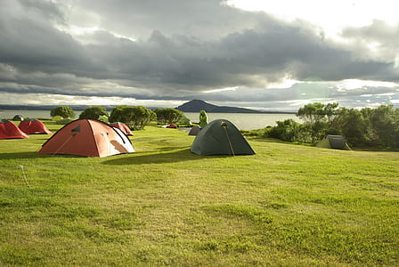 four red and one green tent setups on grass field thumbnail