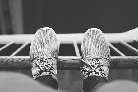 grayscale photo of person's pair of shoes on wood panel thumbnail