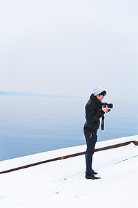 person holding DSLR camera standing under blue sky thumbnail