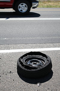 stripped vehicle tire on road near vehicle thumbnail