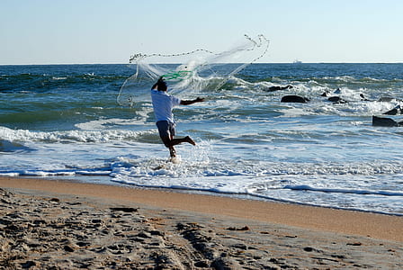 person throw fish net in body of water during daytime thumbnail
