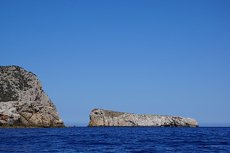 two brown rock mountains in the middle of body of water thumbnail