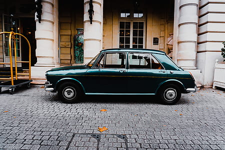 green sedan parked near white concrete building during daytime thumbnail