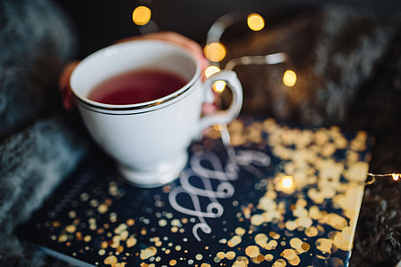 Young woman at home reading Hygge book and drinking thumbnail