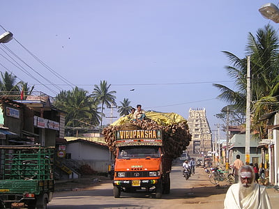 orange truck on road with two men on top of its roof thumbnail