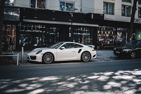 white Porsche 911 coupe parking on road near buildings thumbnail