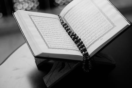 grayscale photography of white book with tesbih prayer beads bookmark on top thumbnail